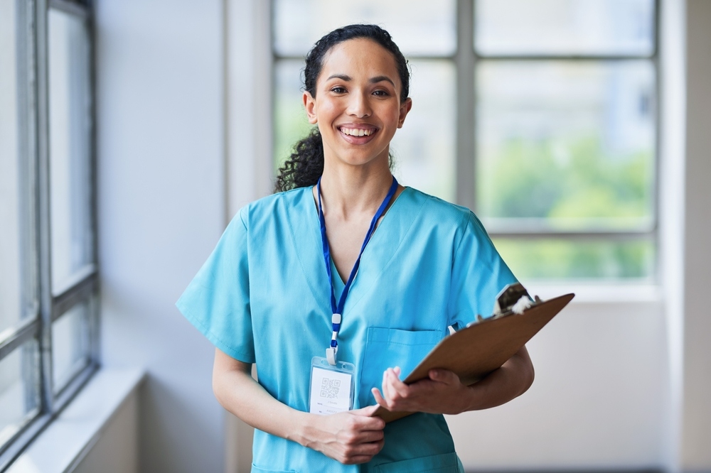 Smiling young nurse in teal scrubs holding a clipboard, representing a new RN graduate ready to start a private duty nursing for new graduates career