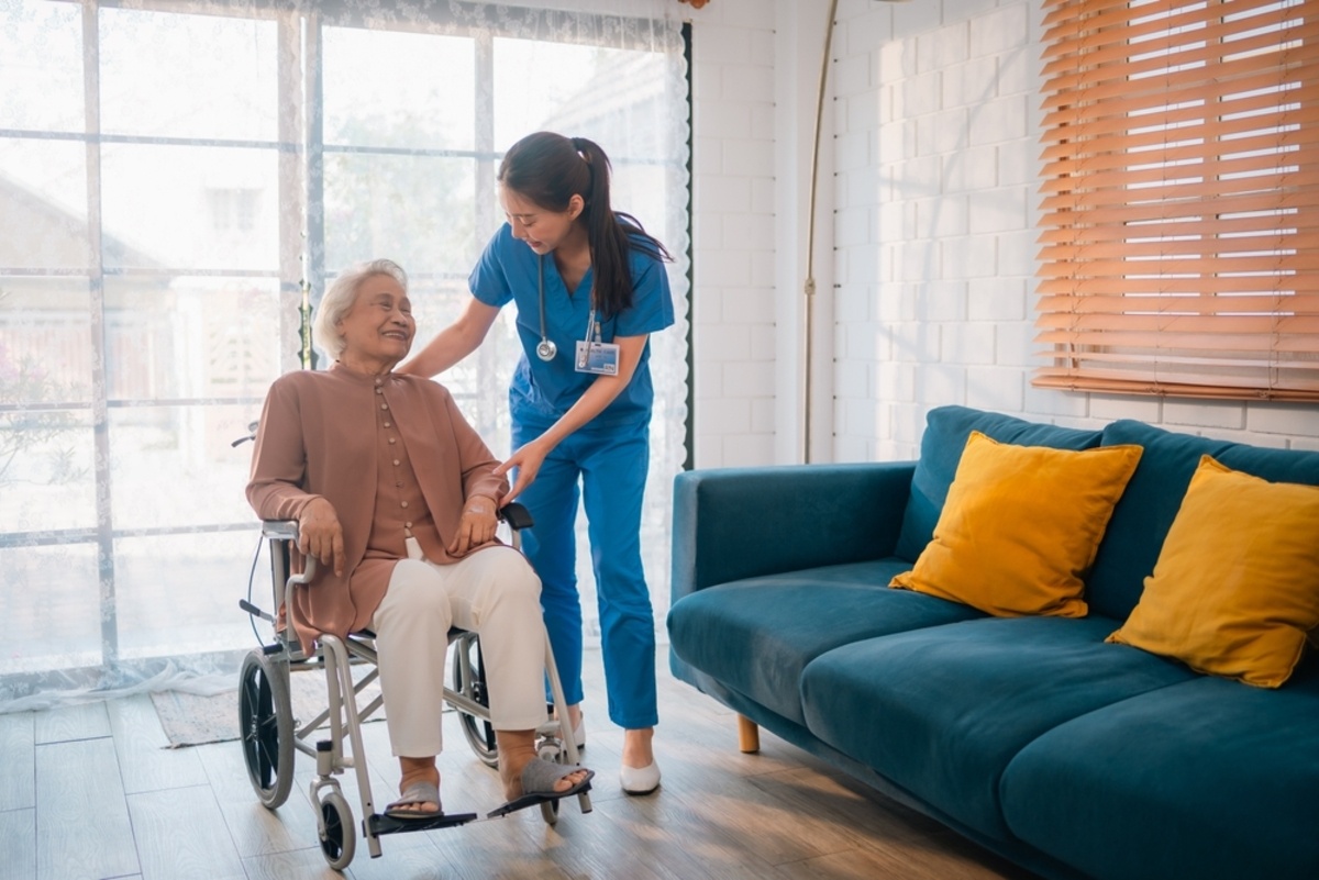 Licensed practical nurse assisting an elderly female patient in a wheelchair during a home care visit, demonstrating LPN home care scope of practice