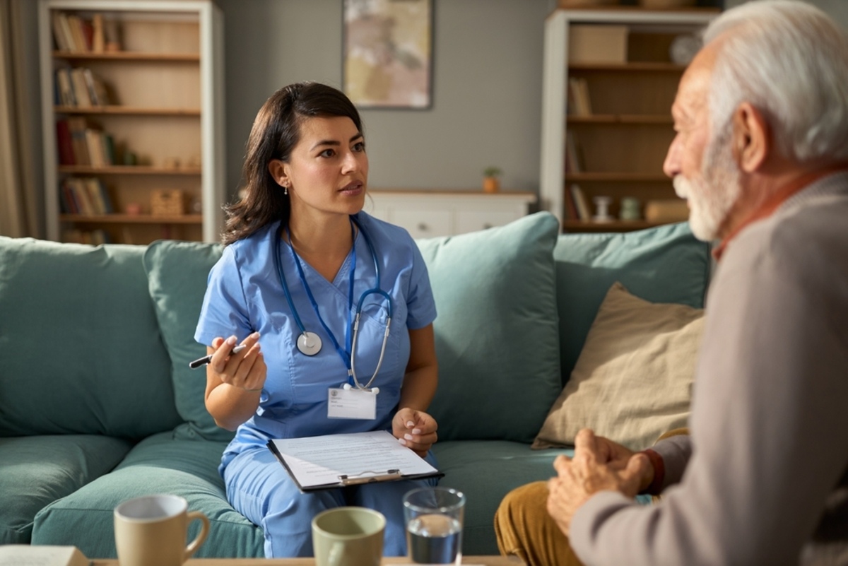 Private duty nurse reviewing care documentation with an elderly male patient as part of her private duty nurse duties during a home shift