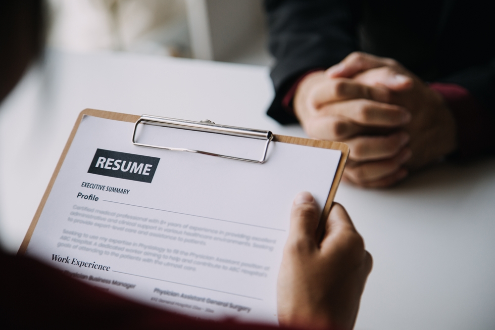 Close-up of a resume on a clipboard being reviewed during a job interview, representing the importance of a strong LPN resume for home care positions